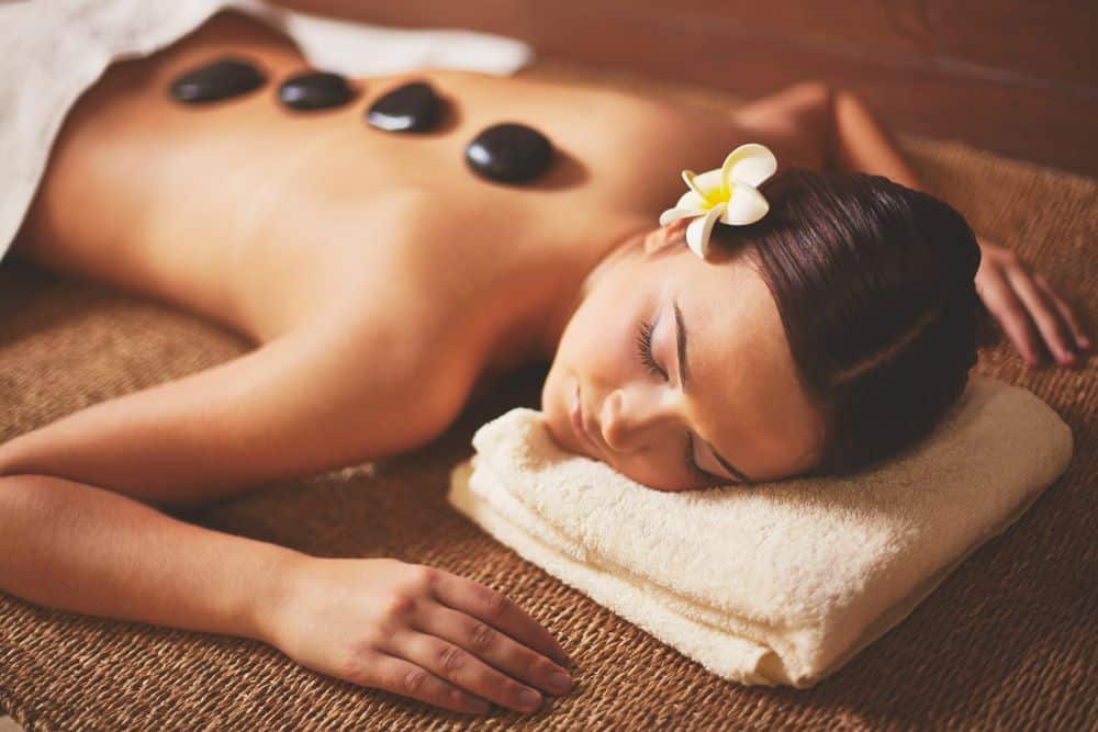 young woman with hot stones massage being performed. spa experiences