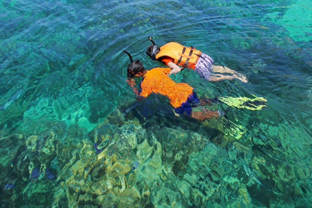two people snorkling in the sea at a beach