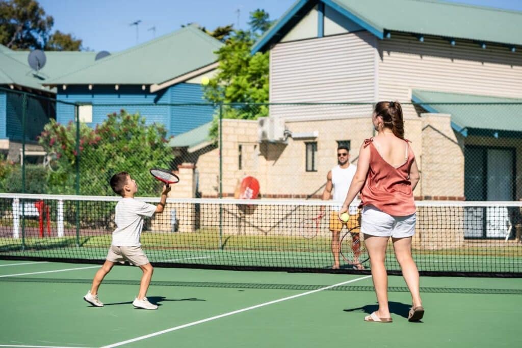 A family playing tennis on the court at Amalfi Resort in Busselton.